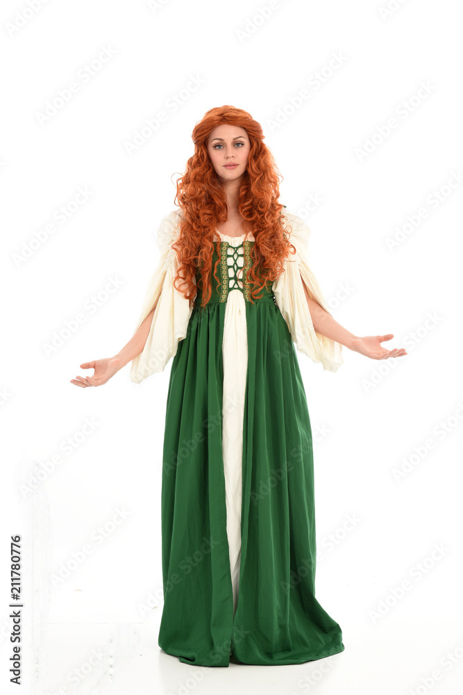 full length portrait of red haired girl wearing long green medieval gown. standing pose, isolated on white studio background. full length portrait of red haired girl wearing long green medieval gown. standing pose, isolated on white studio background.