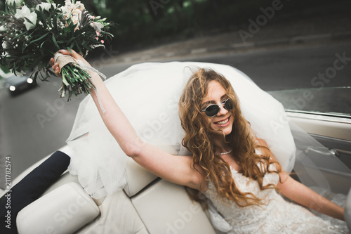 Happy bride in the retro car posing on her weeding day