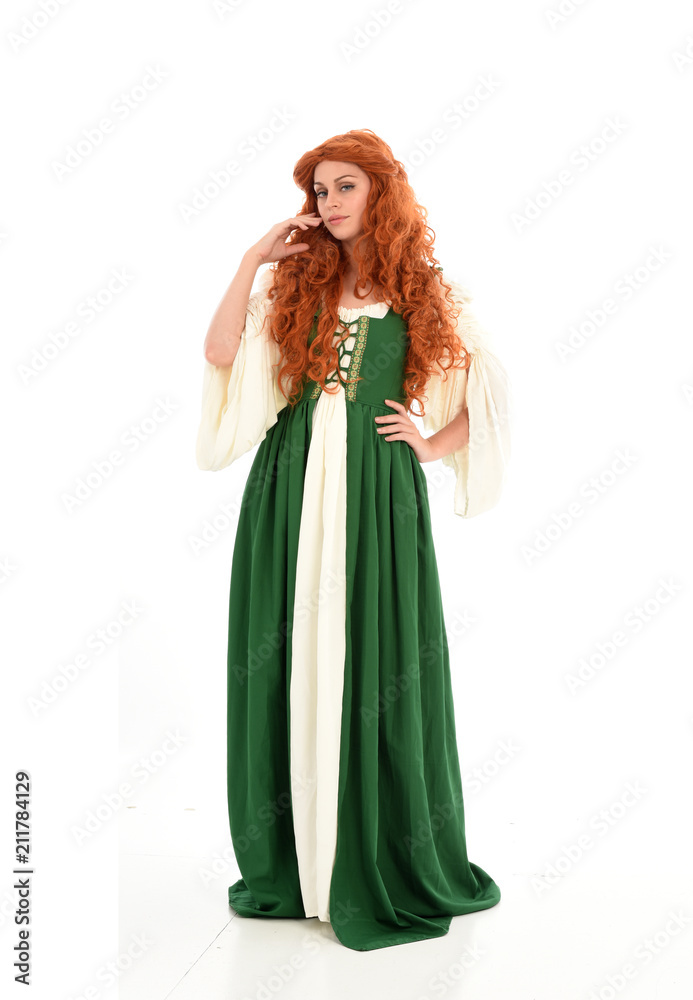 full length portrait of red haired girl wearing long green medieval gown. standing pose, isolated on white studio background.