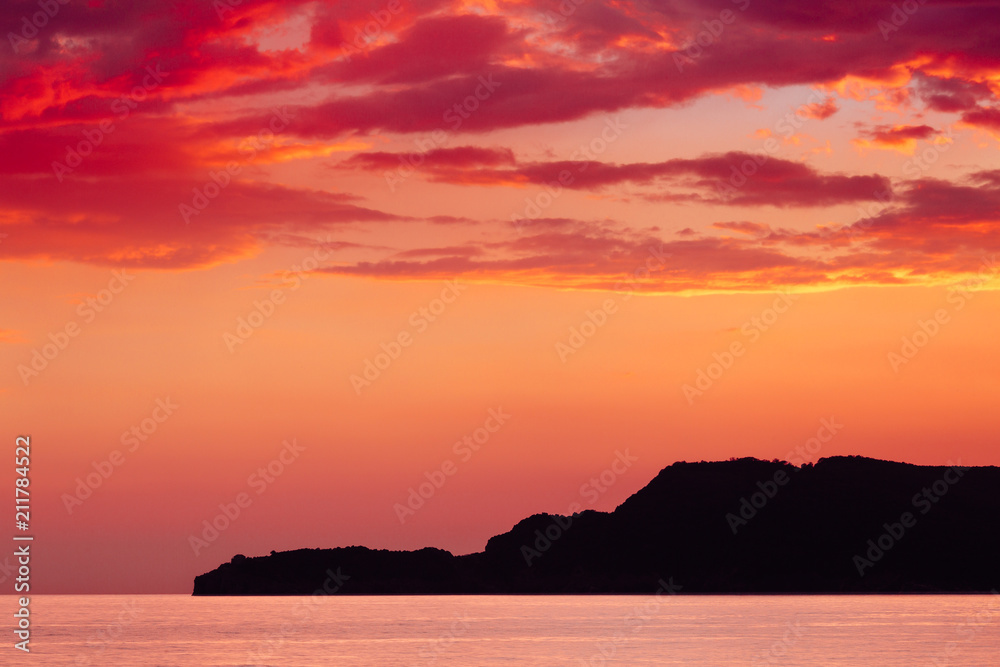 Sunset over the sea with beautiful red clouds in Sveti Stefan, Montenegro