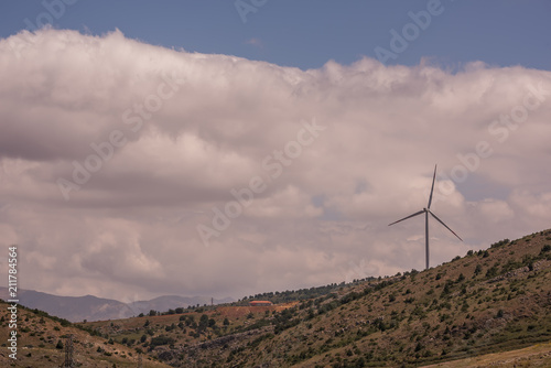 Wind power generator on a hill in the background of mountains. 