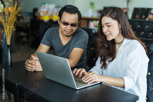 man and woman using laptop in cafe