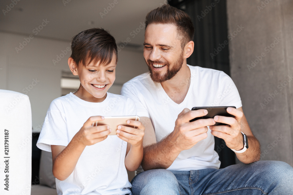 Handsome bearded man indoors at home with his son Handsome bearded man indoors at home with his son