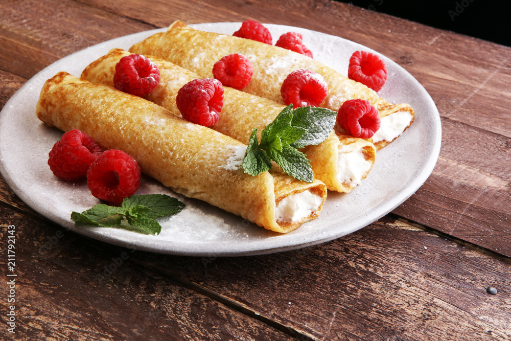 Homemade crepes served with fresh raspberrries and powdered sugar on rustic wooden table Homemade crepes served with fresh raspberrries and powdered sugar on rustic wooden table
