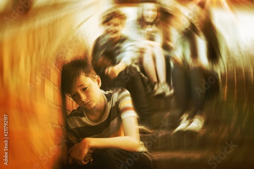 School friends bullying a sad boy in school corridor photo