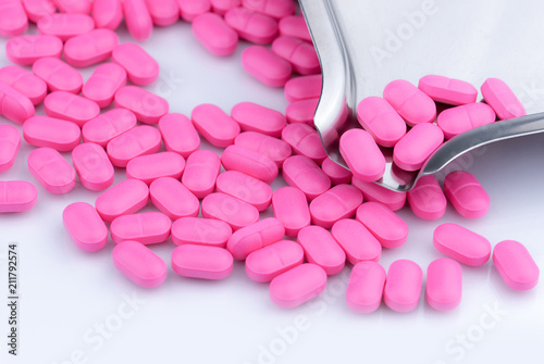 Pile of pink tablets pill on white background near stainless steel drug tray. Norfloxacin 400 mg for treatment cystitis. Antibiotics drug resistance. Antimicrobial drug use with reasonable concept.