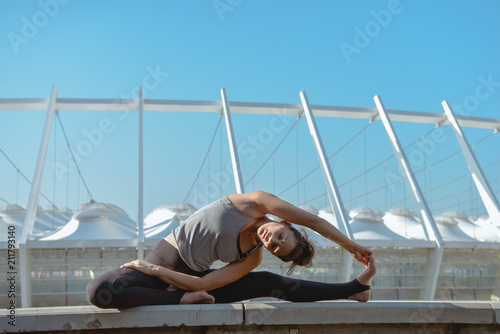 Woman doing yoga exercises outdoors at stadium.Beautiful brunette fit young woman wearing sportswear practicing yoga urban style.Asana, working out,fitness,sport,training and lifestyle concept
