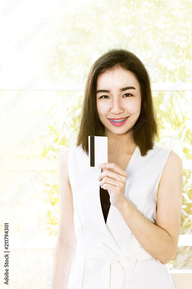 Portrait woman in black and white suit holding colored shopping credit card.Girl looking smiling and strong.Copy space. Portrait woman in black and white suit holding colored shopping credit card.Girl looking smiling and strong.Copy space.