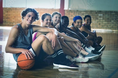 Fototapeta Naklejka Na Ścianę i Meble -  High school kids sitting on the floor in basketball court