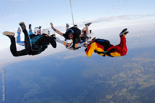 Group of skydivers is in the sky. Friends are falling with tandem-passenger girl.