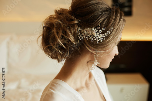 Wedding hairstyle of beautiful and fashionable brown-haired model girl in a lace dress, with earrings and jewelry in her hair