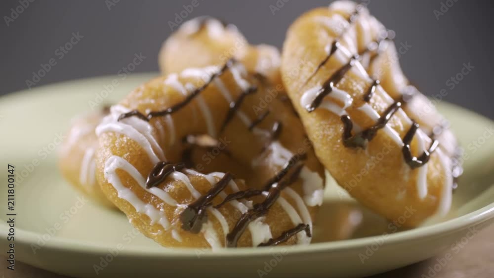 Donuts with white and chocolate icing lie on a plate. Rotation Donuts with white and chocolate icing lie on a plate. Rotation