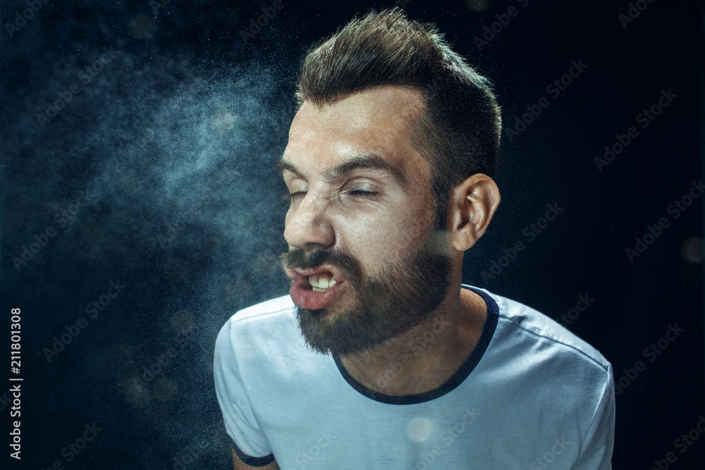 Young handsome man with beard sneezing, studio portrait Young handsome man with beard sneezing, studio portrait