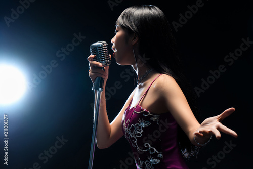 Asian woman singer holding a microphone singing.
