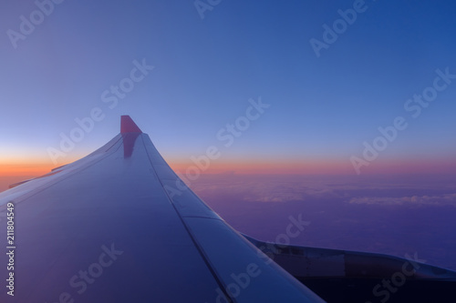 Wing of the airplane in blue skies at sunset background.