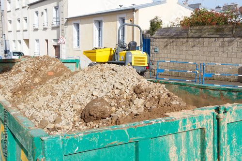 Benne à gravats et tombereau dans une rue