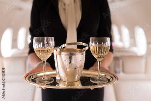 Flight attendant serving glasses of champagne in private jet