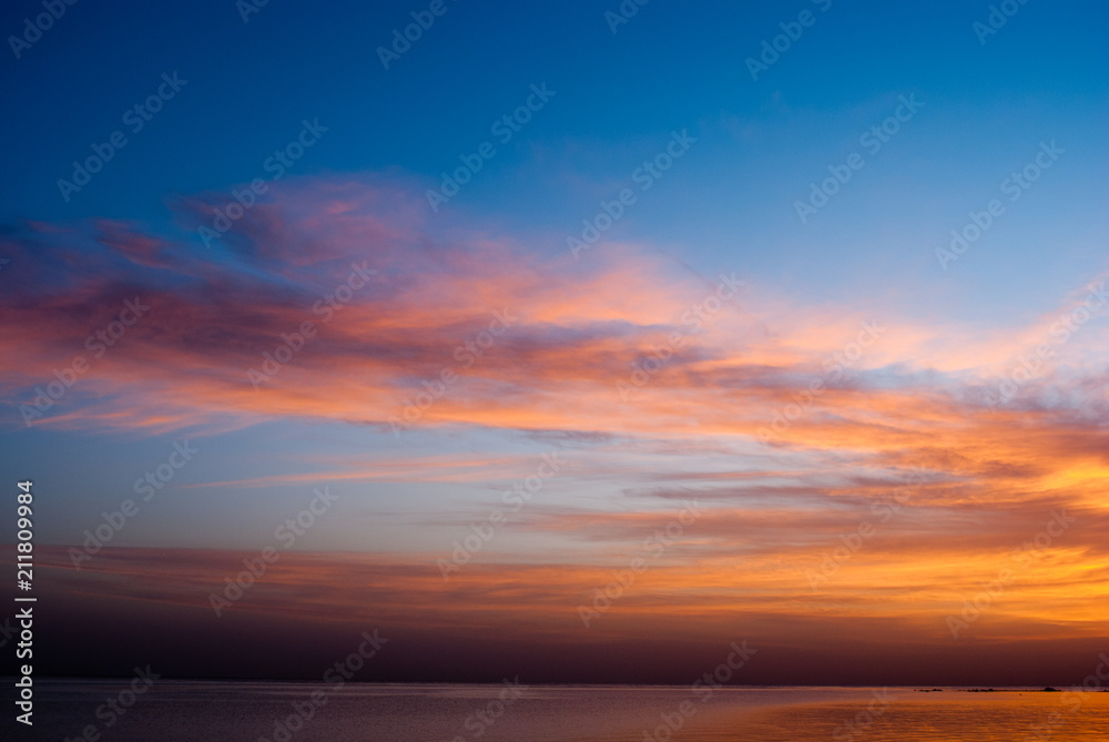 Red sunrise in blue sky above ocean. Morning early blue sky with clouds morning on sea. Sunrise on blue sky and cold water.