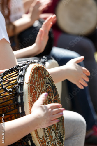close-up of people's hands playing on African djembe drums on a sunny summer day. group of people with African drums musical instrument