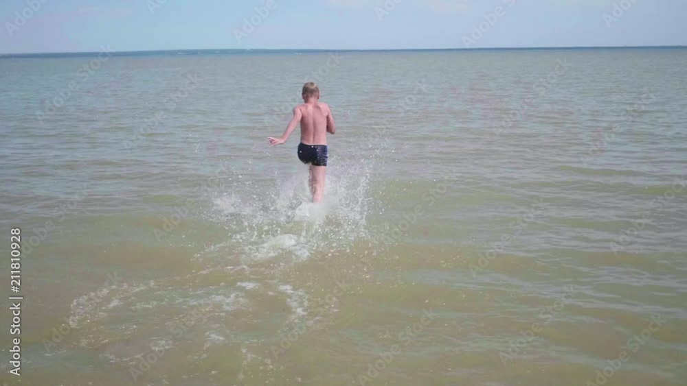 happy child runs with pleasure on the beach. Water spray, hot summer day happy child runs with pleasure on the beach. Water spray, hot summer day