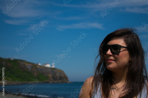 young woman with dark hair and sunglasses looking on beautiful landscape © Maciej