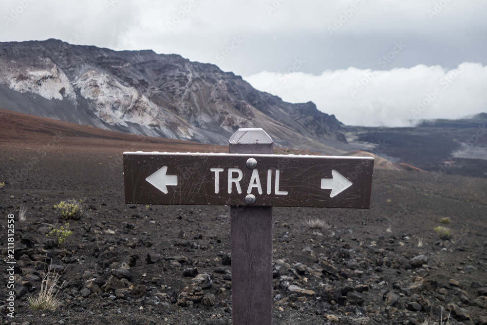 water drops on trail sign with arrows Maui Volcano with clouds in the sky and in mountain tops water drops on trail sign with arrows Maui Volcano with clouds in the sky and in mountain tops
