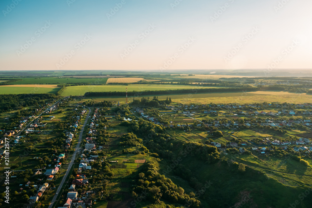 Aerial view from drone or aerostat to summer nature landscape panorama, green meadows, roads, houses in countryside at sunset time, travel background