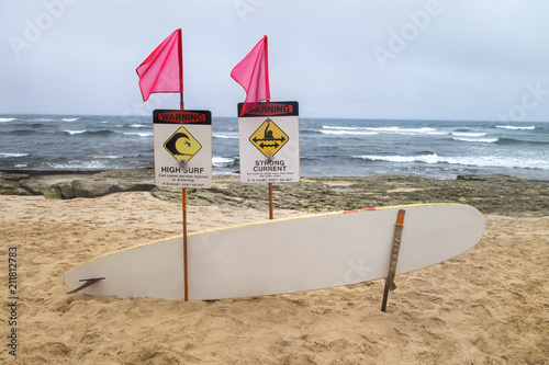 flaged high surf, strong curent warning signs with rescue surfboard alone tourest island beach area