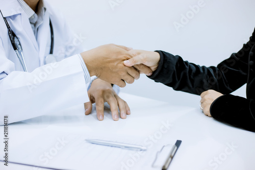 Doctor and patient shaking hands to patient in the office at desk