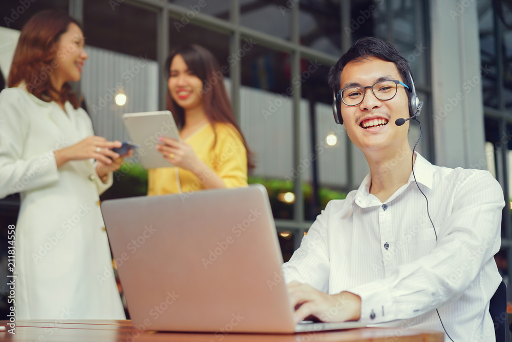 close up asian call center man smiling with teamwork meeting behind at office 