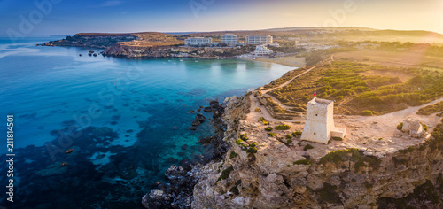 Ghajn Tuffieha, Malta - Aerial panoramic view of the coast of Ghajn Tuffieha with Watch Tower, Golden Bay beach and crystal clear sea water at sunrise