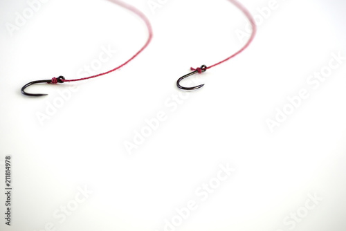 Fishing hook, red rope on white background, with empty space.