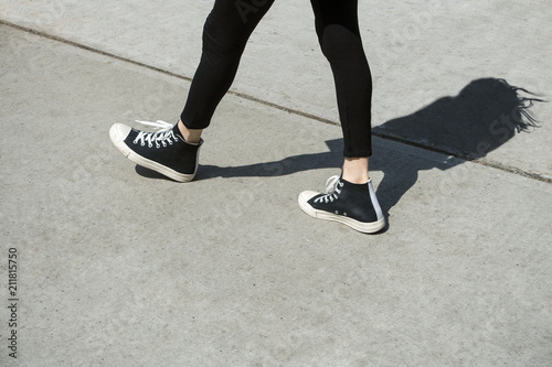 shadow of a woman in stride on urban city cement walkway