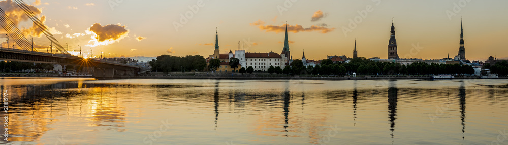 Panoramic view on historical district of old Riga city from left bank of the Daugava river, colorful sunrise