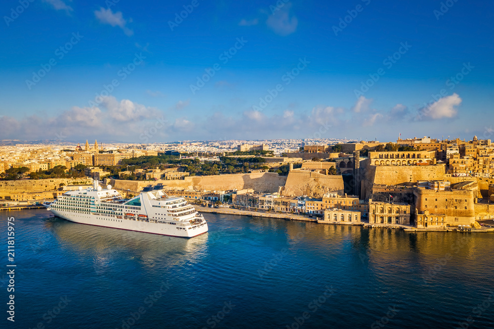 Valletta, Malta - Cruise ship in the Grand Harbor at sunrise with the ancient city of Valletta at background