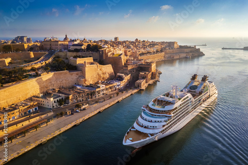 Valletta, Malta - Cruise ship sailing into Grand Harbor at sunrise with the ancient city of Valletta at background