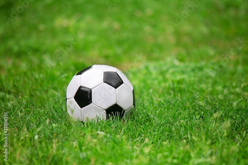 football ball lying on the green grass © Dudzenich