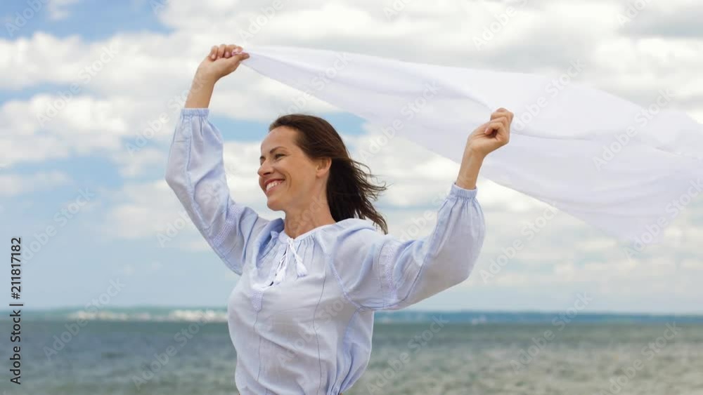 people and leisure concept - happy woman with shawl waving in wind on summer beach people and leisure concept - happy woman with shawl waving in wind on summer beach