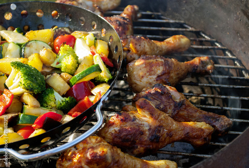 Barbecue / Grillparty im Sommer mit gegrillten Hähnchenkeulen und gemischtem Gemüse auf Holzkohlegrill 
