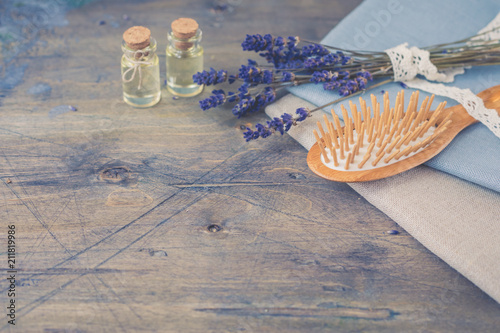 Wooden Scalp and Massage brush and comb and hair oil with natural lavender on the rustic background