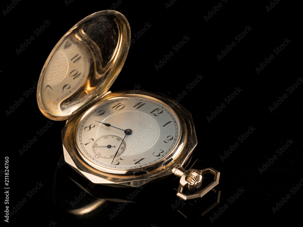 Old golden pocket watch on a black reflective surface Old golden pocket watch on a black reflective surface