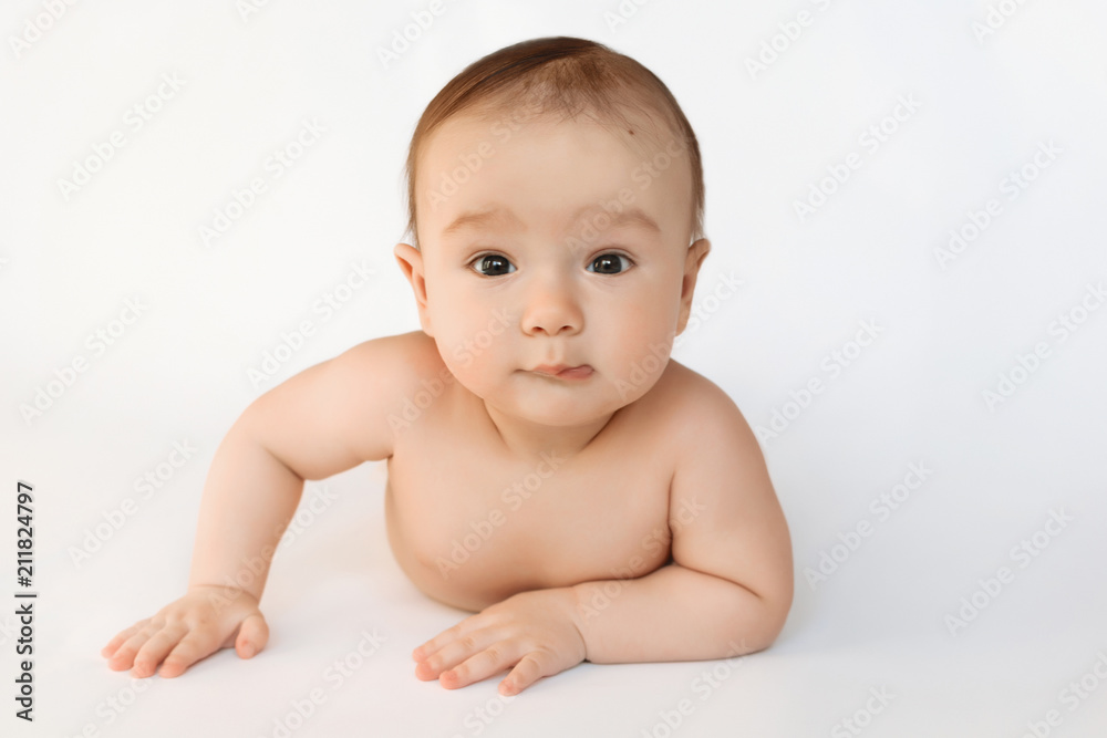 Portrait of an infant baby biting his lip and laying on a belly. Happy childhood concept Portrait of an infant baby biting his lip and laying on a belly. Happy childhood concept