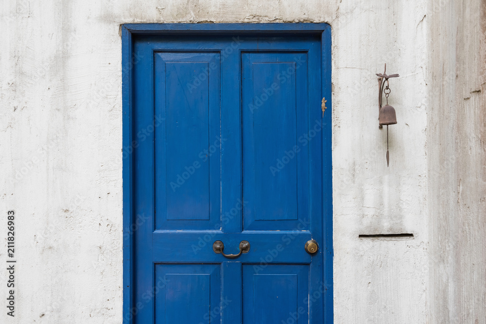 Antique blue door and old bell on wall