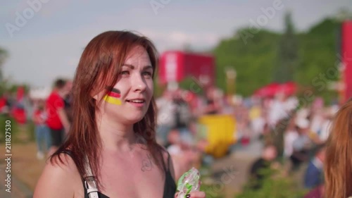 Young woman with german flag painted on cheeck is disappointed with game