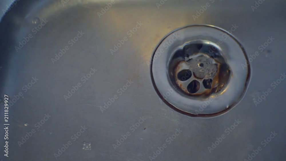 Stainless steel sink plug hole close up with water Stainless steel sink plug hole close up with water