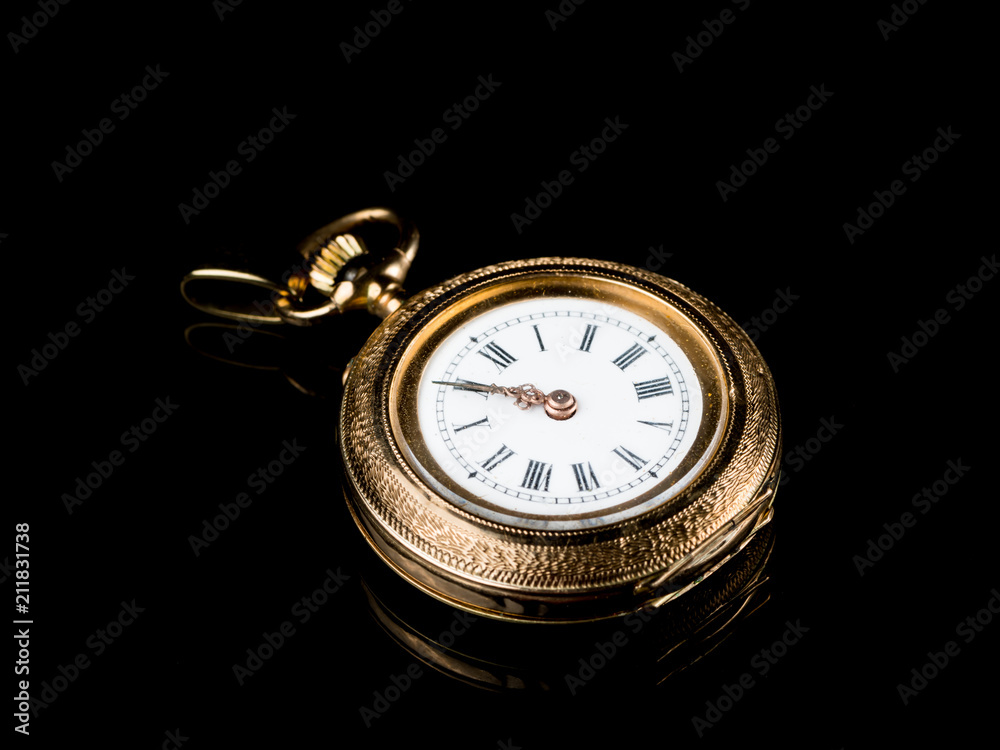 Old golden pocket watch on a black reflective surface Old golden pocket watch on a black reflective surface