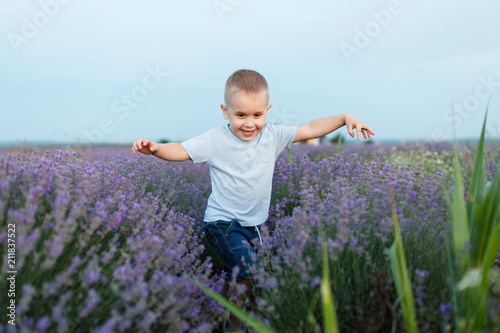 Fototapeta Naklejka Na Ścianę i Meble -  Playful little cute child baby boy walk on purple lavender flower meadow field background, run, have fun, play, enjoy. Excited small kid son. Family day, kids, children, childhood, lifestyle concept.