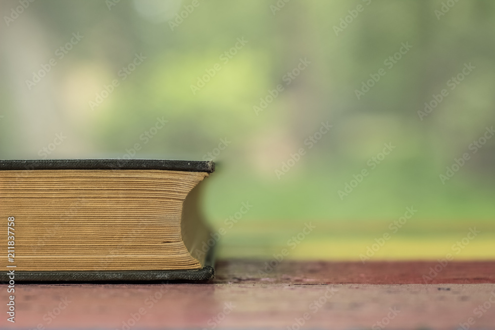 soft focus vintage old book's spine concept on colorful wooden table and unfocused blurred nature background with empty space for copy or text
