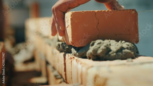 The builder's hand puts the brick in the masonry of the wall.