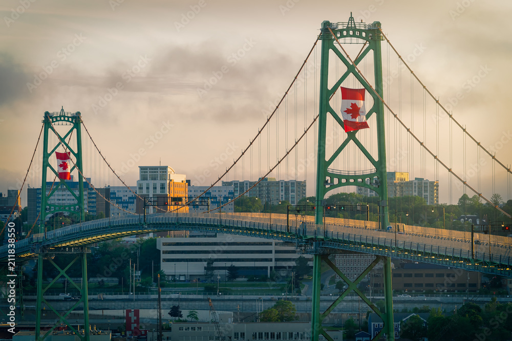 The Angus L MacDonald Bridge at dusk on Canada Day with large Canadian flags flying. - obrazy, fototapety, plakaty 